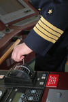 Foto, Bild: Kapitn mit vier Streifen am Uniformrmel am Maschinentelegraph (Maschinentelegraf, Fahrstufenregler)