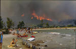 Foto, Bild: Urlauber am Strand vor den brennenden Bergen