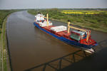 Nord-Ostsee-Kanal (Kiel Canal) mit Feederschiff SUDEROOG und Rapsfeld